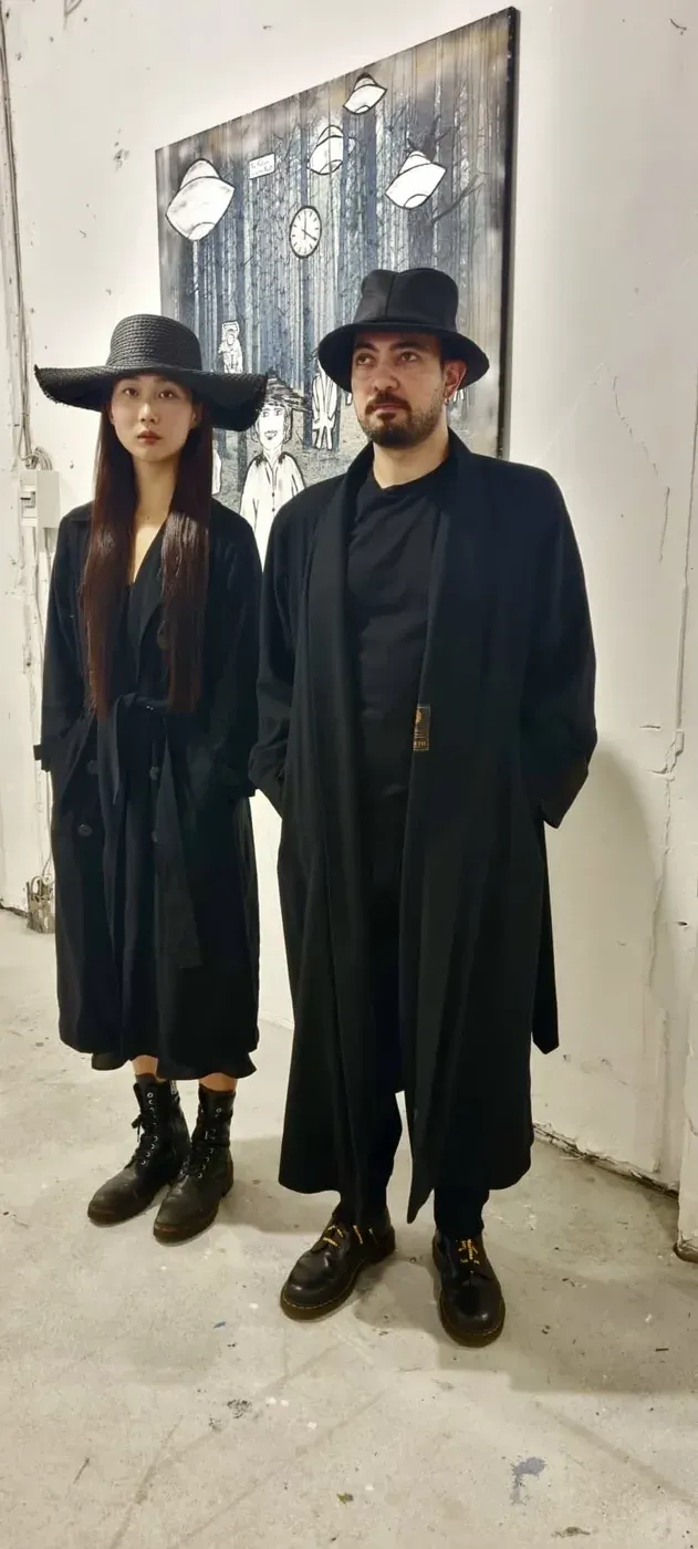 Two time travellers stand in front of a work by Suzy Forel during an exhibition